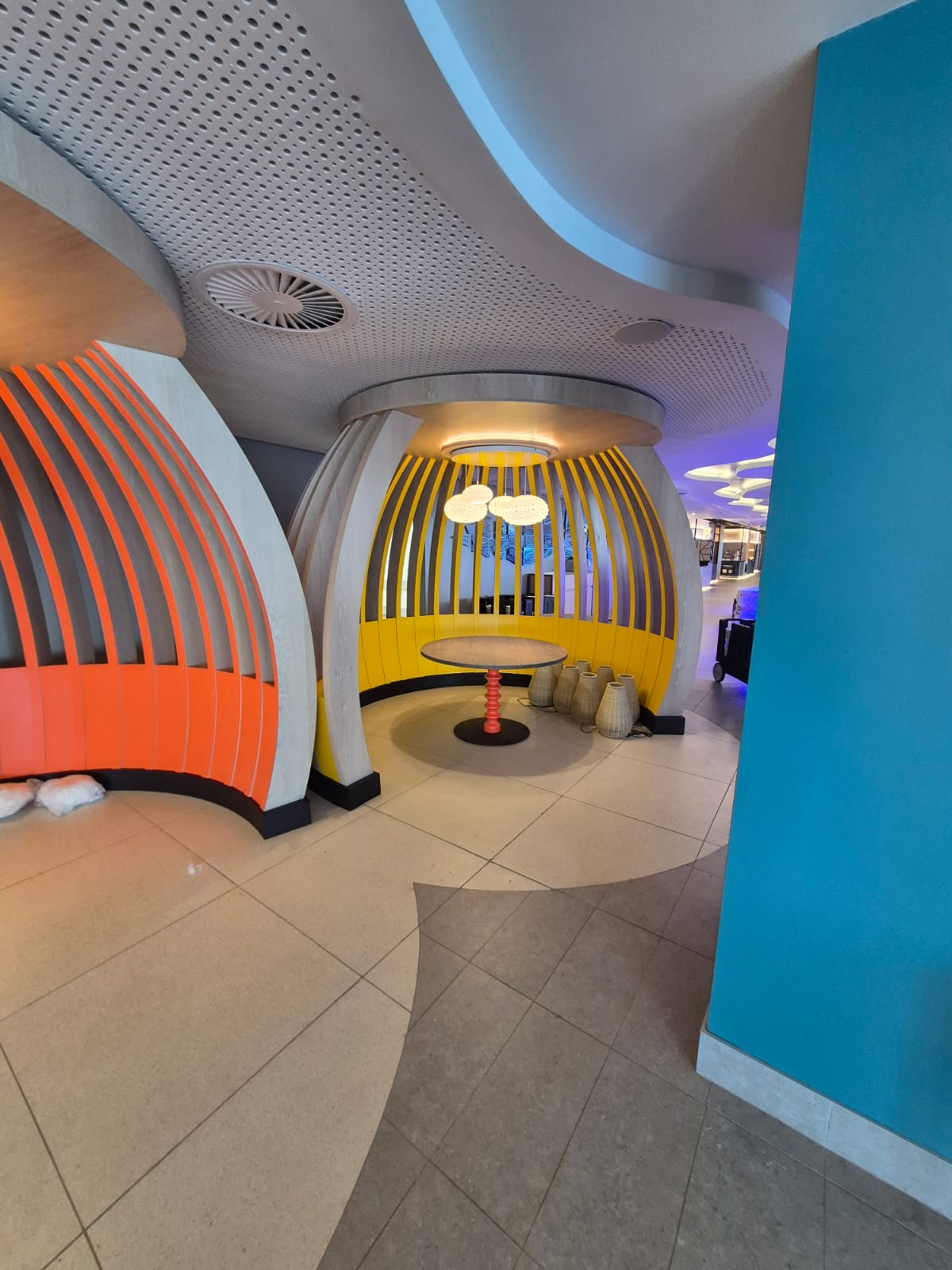 Orange and yellow slatted cocoon booths with pendant lighting and pedestal tables